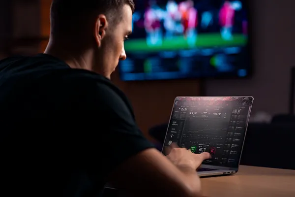 A man celebrating a winning moment on his laptop while gaming symbols float around him, capturing the excitement of JEETA games.